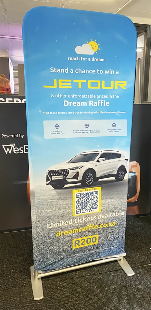 A sock-banner displayed at the Festival of Motoring at the Kyalami Racetrack, provided by Brand Monster to Reach For a Dream. The sock-banner promotes RFAD's car giveaway competition.